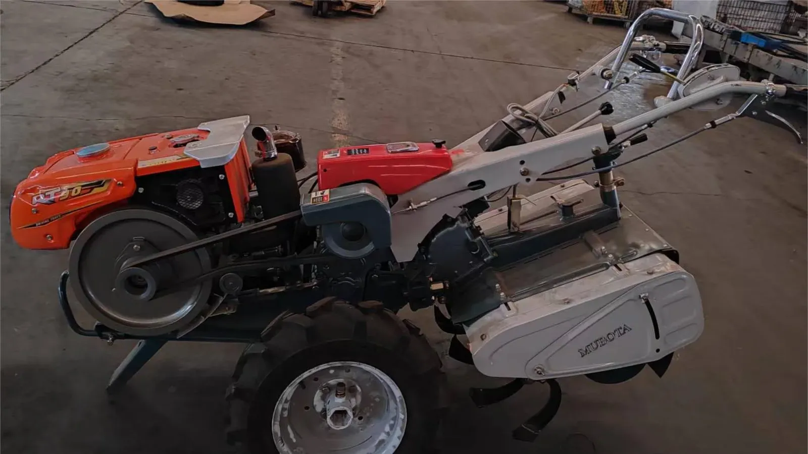 A complete M80 power tiller with its diesel engine, belt drive and rotary tiller fitted, photographed on a factory floor before delivery