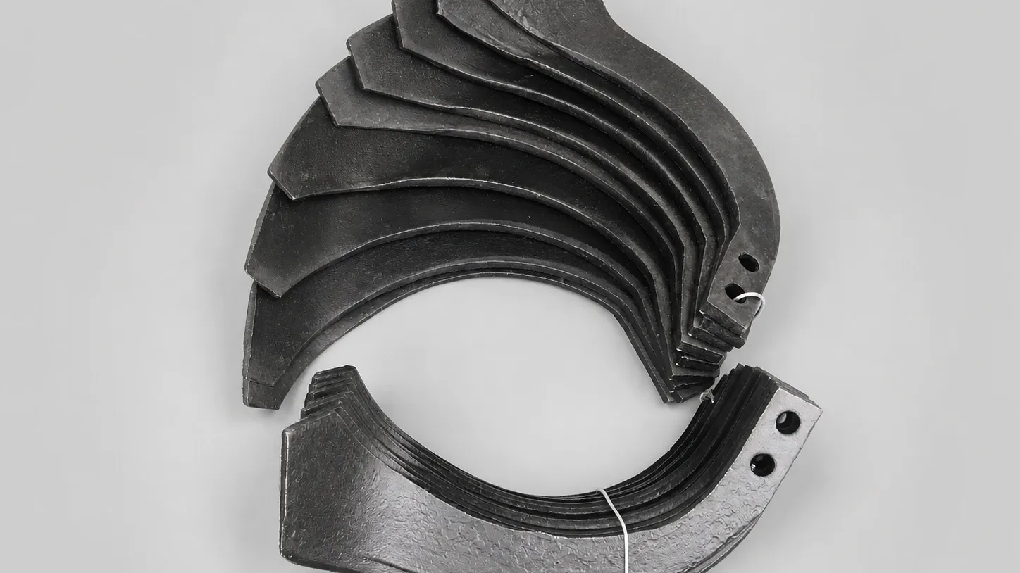A stack of curved rotary tiller blades for a two-wheel power tiller, showing the edge bevel and the two mounting holes in the shank