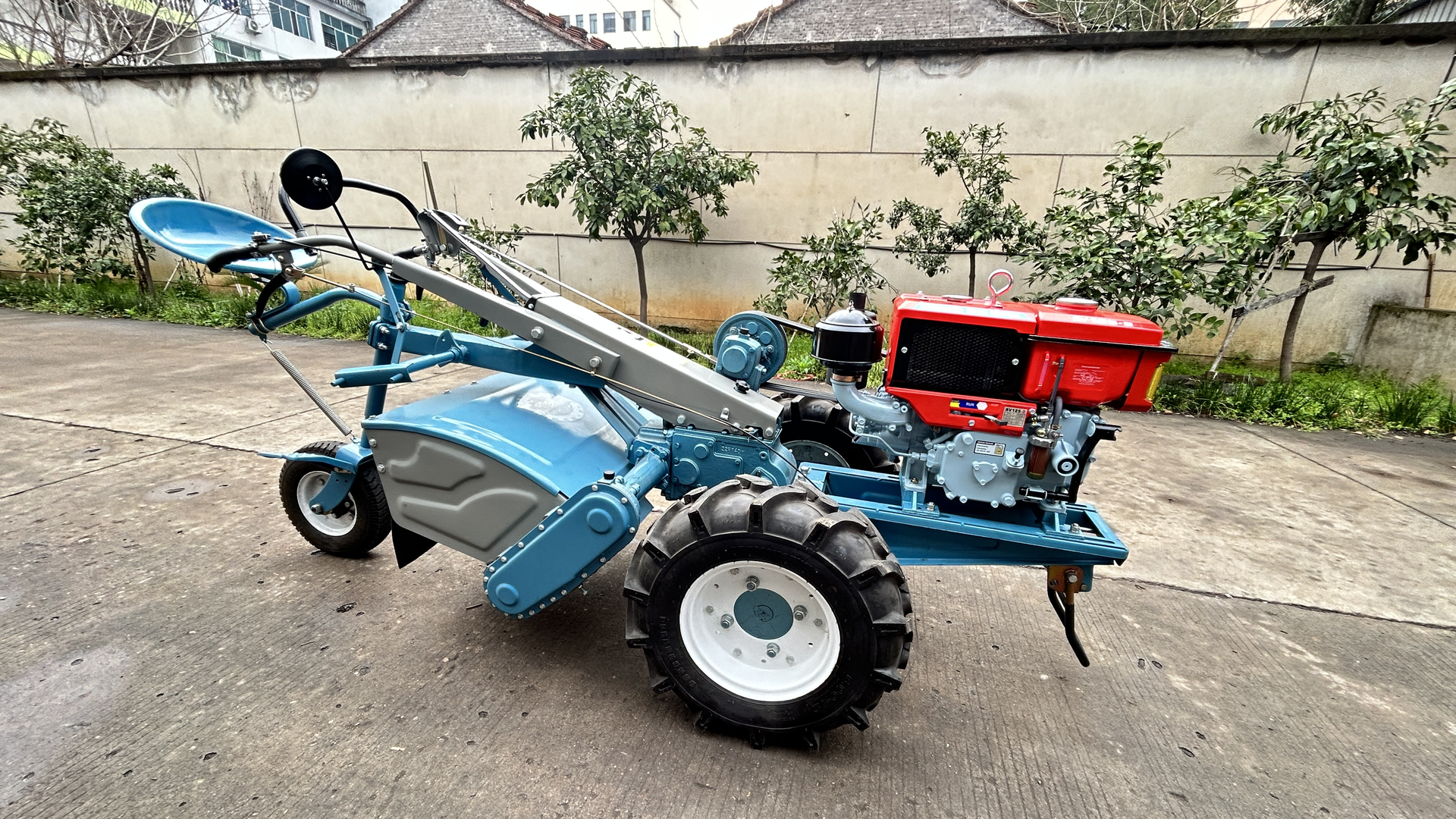 A blue SUNTEC walking tractor with its diesel engine and rotary cultivator housing fitted, photographed on the yard before delivery